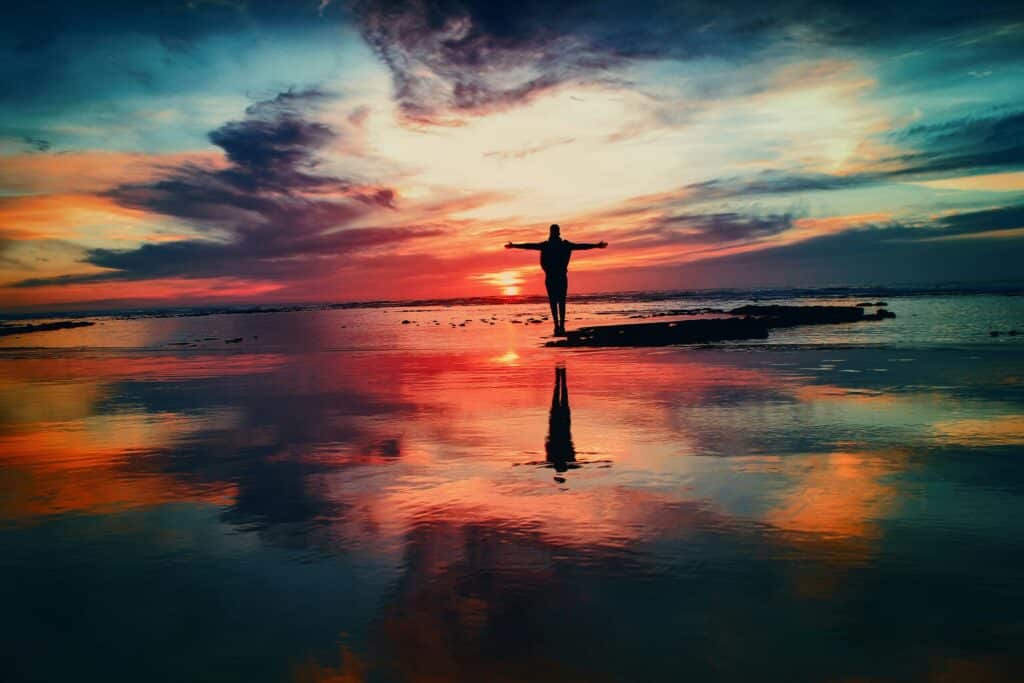 cbt for overeating represented by a man standing arms wide open on the beach at sunset