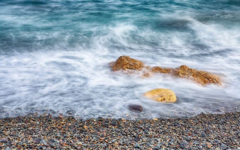 Ocean tides gently receding over a smooth pebble beach, symbolising recovery from binge eating and purging disorder