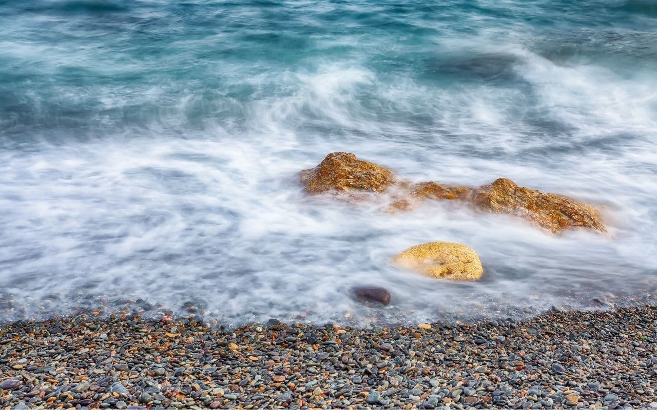 Ocean tides gently receding over a smooth pebble beach, symbolising recovery from binge eating and purging disorder