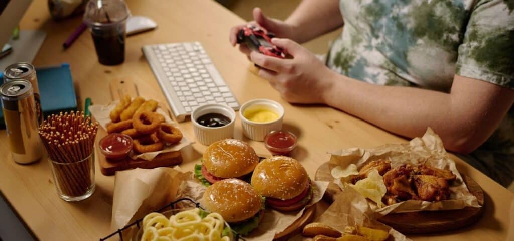 adhd and binge eating - person eating playing video games