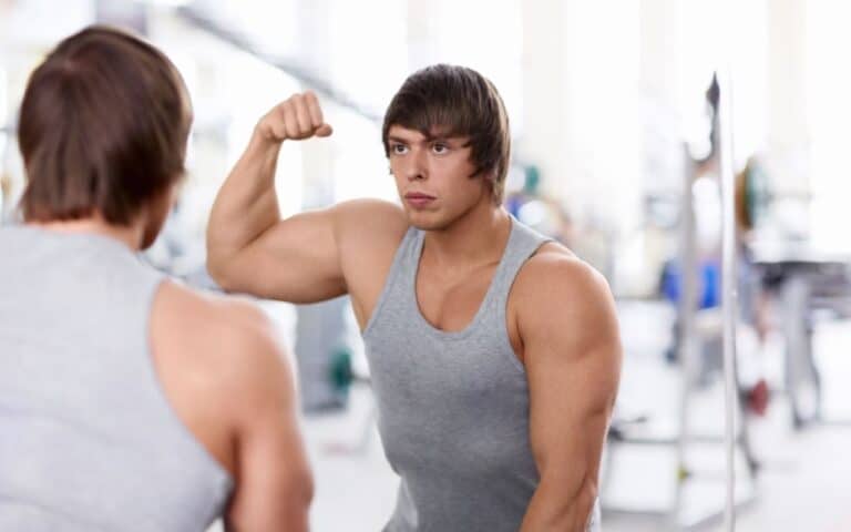 body dysmorphia men - man flexing muscles in mirror