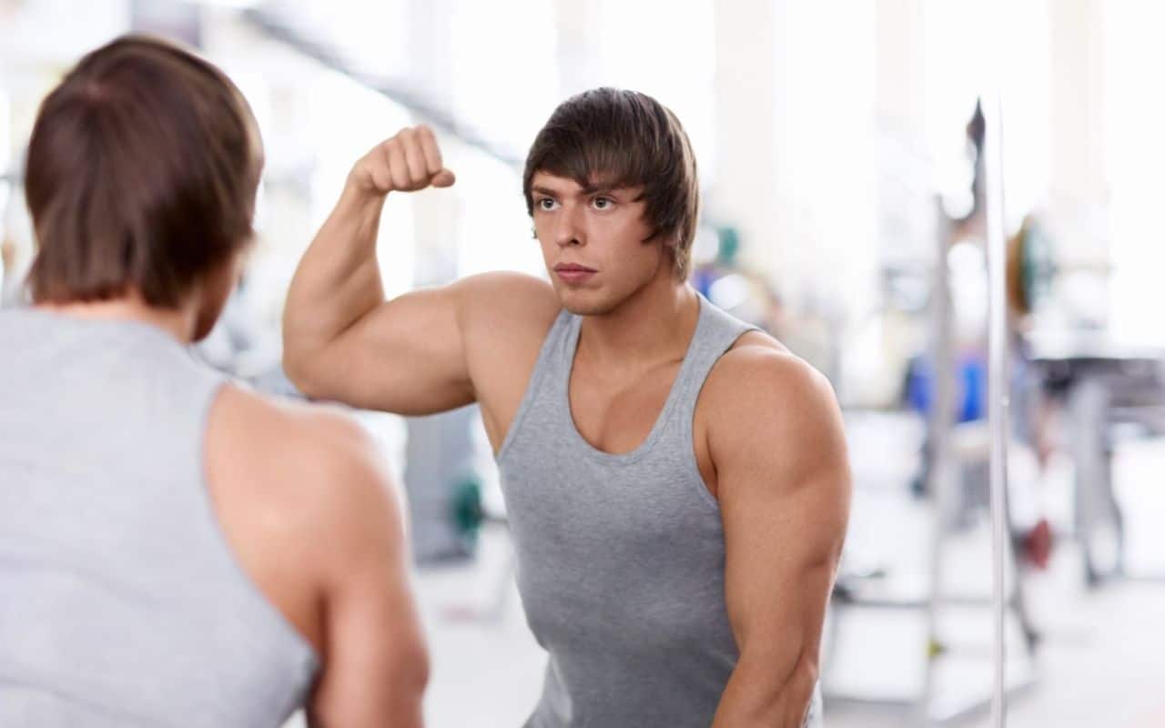 body dysmorphia men - man flexing muscles in mirror