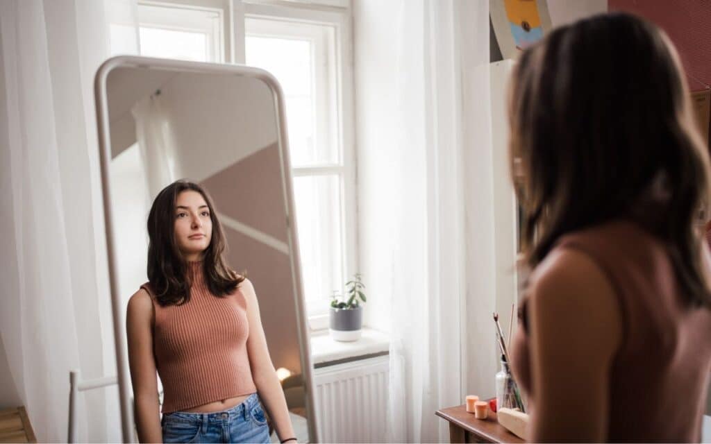 how to deal with body dysmorphia - girl looking in the mirror