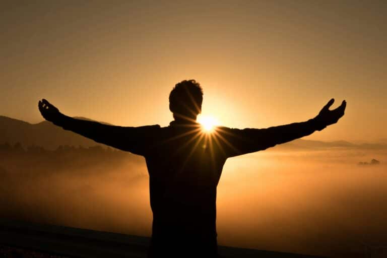 breaking the cycle of depression and binge eating represented by a man with arms wide at sunset